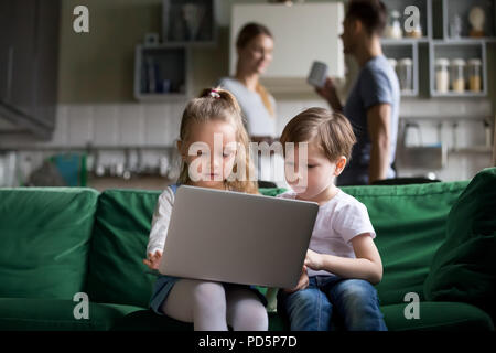 Cute children sister and brother holding laptop watching online  Stock Photo