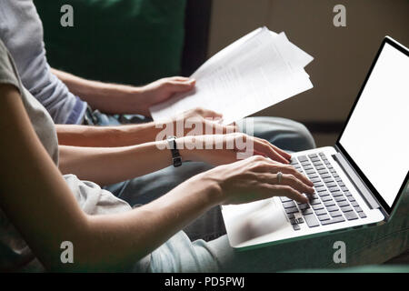 Couple holding reading documents at home with laptop, close up Stock Photo