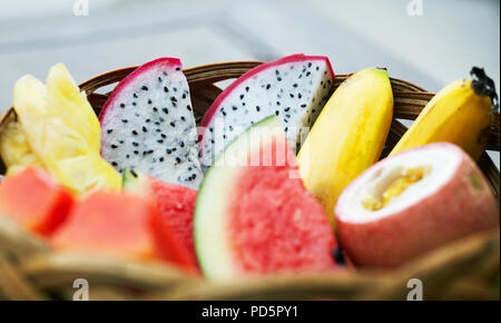 Sliced mix of tropical fruits in a wicker basket Stock Photo