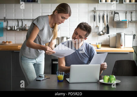 Serious young couple worried discussing utility bills in the kit Stock Photo