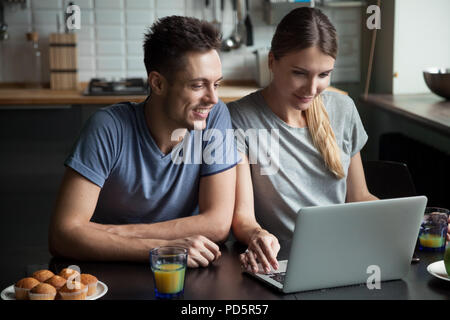 Young couple using laptop together while having breakfast at hom Stock Photo