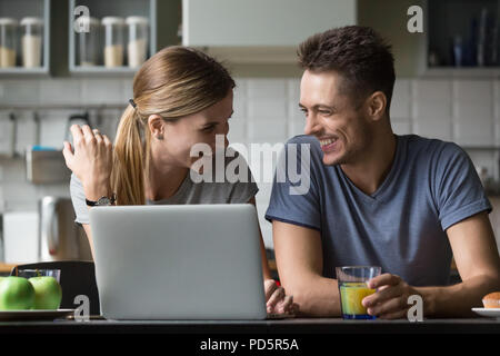 Young happy couple talking and laughing having breakfast with la Stock Photo