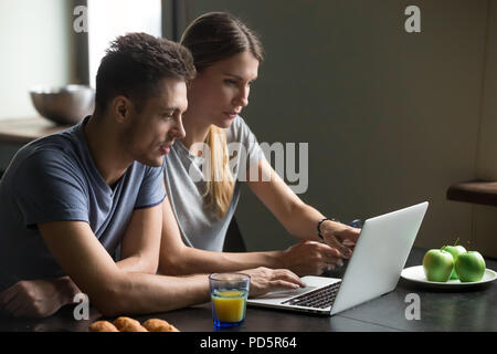 Couple using laptop for reading news or work having breakfast Stock Photo