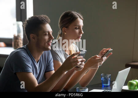 Young couple obsessed using phones apps ignoring each other Stock Photo