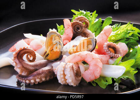 Fresh seafood cocktail in a black plate on a black background Stock Photo
