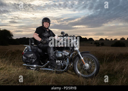 Leather clad biker posing for a photoshoot on his custom Harley Davidson XL883 Sportster Low cruiser motorcycle, on the Beverley westwood, East riding Stock Photo