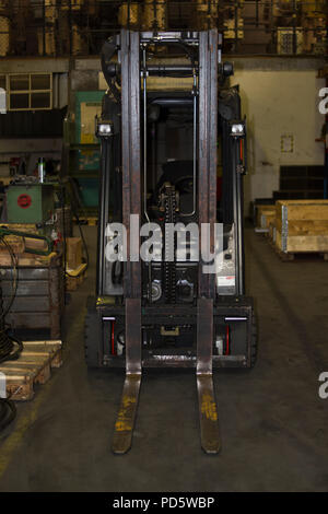 Forklift to transport pallets in an industrial production hall with pallets and boxes Stock Photo