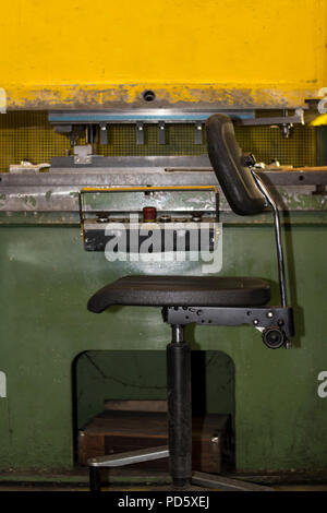 Old rustic yellow vintage retro machine part mechanical construction press for sheet metal steel processing strong press sitting workspace Stock Photo