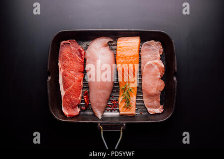 Group of animal proteins, chicken, meat, fish and pork on a black background Stock Photo