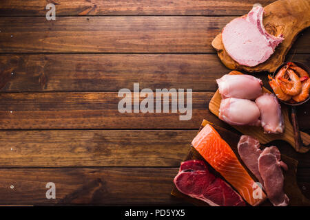 Group of animal proteins, chicken, meat, fish and pork on a wood background Stock Photo