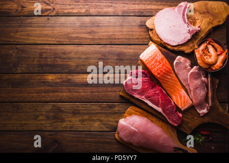 Group of animal proteins, chicken, meat, fish and pork on a wood background Stock Photo