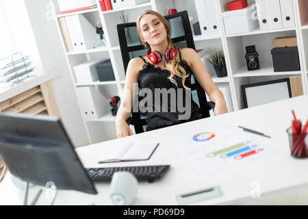 The young girl leaned back in her chair and closed her eyes. the girl on her neck hangs headphones. Stock Photo