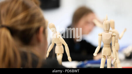 Visual Art high school students working from wooden mannequins practicing drawing human fugure and correct proportion. Artists being creative the art  Stock Photo