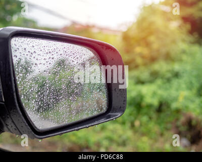 Water drops, Rain drops on side rear view mirror on car with tree background Stock Photo