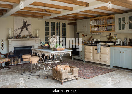 Light blue fitted farmhouse kitchen with plate rack and artwork of kitchen knives above fireplace. Stock Photo