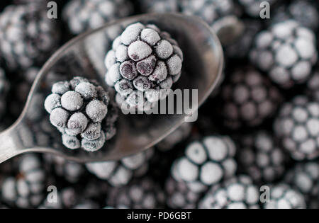 Frozen blackberries on a spoon with blackberries background Stock Photo