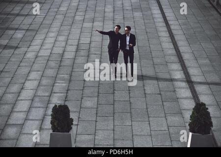 Portrait of two businessmen discussing about the new project while walking outdoors. Stock Photo