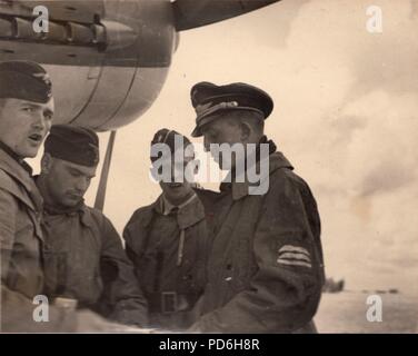 Image from the photo album of Oberleutnant Oscar Müller of  Kampfgeschwader 1: Leutnant Oscar Müller (second from right) in discussion with Oberleutnant Karl Heinz Müncheberg (right) and his crew, autumn 1941. Müncheberg was Staffelkapitän of 5./KG 1 after Oberleutnant Clodius was lost on 8th November 1941. Müncheberg was shot down by anti-aircraft fire and killed on 17th December 1941. Stock Photo