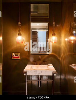 Coloured glass pendant shades with mirror above marble sink. Stock Photo