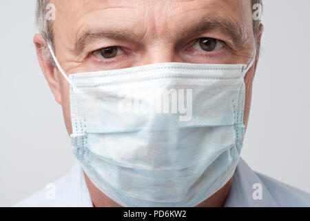 Close up portrait of serious man in special medic mask. He is looking serious. Mature experienced doctor. Medicine, healthcare and emergency in hospit Stock Photo