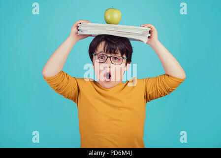 little boy with green apple and books on blue background Stock Photo