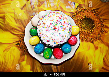 Top view of Easter cake and Easter painted eggs. Traditional Easter food on holiday table background. Stock Photo