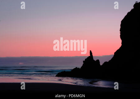 Amazing sunset with pastallic rose colors at the black beach of Piha north of Auckland in New Zealand Stock Photo