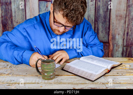 Man reading Bible in the church behind a wooden table Stock Photo