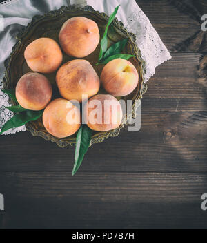 fresh ripe peaches in a round iron plate, vintage toning, copy space Stock Photo