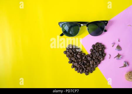top view flat layer funny face made from coffee beans in smile  icon shape , and sun glasses on two tone multicoloured  background Stock Photo