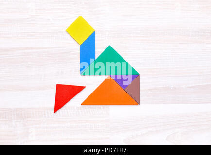 From above shot tangram figures into shape of house on wooden table without one piece. Stock Photo