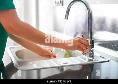 Woman pouring the water to the cup for drink in the kitchen. Close up Stock Photo