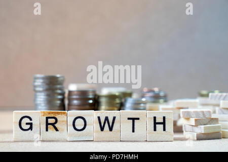Growth Word Written In Wooden Cube on wood table with money stack up as graphs in background Stock Photo