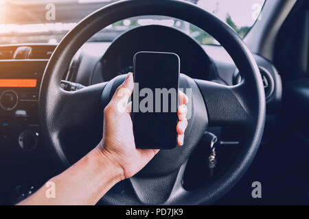 Hand holding smartphone in car parked on street.And using smartphone to shopping online by internet Stock Photo