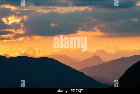 The Alps at sunrise. Colorful sky majestic mountain peaks, fog mist valleys. Sunburst and backlight expansive view from above. Stock Photo