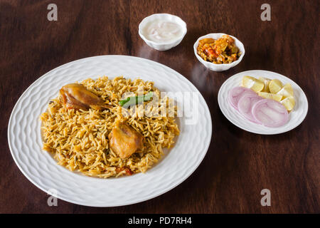Overhead view from the top of delicious Indian chicken biryani served with traditional sides, salad (raita) and gravy. Natural light used. Stock Photo