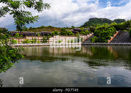Buddhist Temple in Ninh Binh province, with lake and engraving on a long wall by the lake Stock Photo