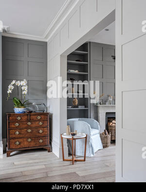 Antique chest in open plan living room with wall panelling and scrubbed wooden floors, the round wooden side table is from Linley Stock Photo