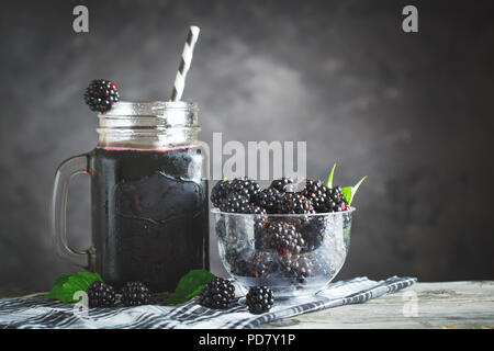 Ripe blackberry and blackberry juice on a wooden table. Dark background. Dark background. Selective focus. Background with copy space. Stock Photo