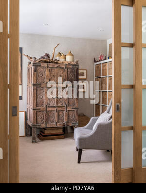 View through slidiing doors into home office with lots of wall shelving and an old wooden chest from Oman in entrance lobby. Stock Photo