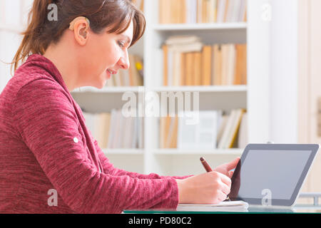 Hearing impaired woman working with tablet at home or office Stock Photo