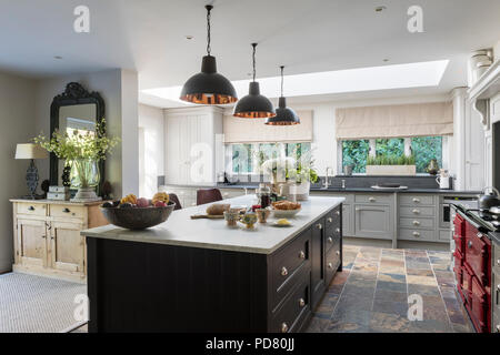 Bespoke kitchen island by Thomas Ford & Sons is painted in Tanner's Brown by Farrow & Ball. Industrial style pendant lights hang above Stock Photo