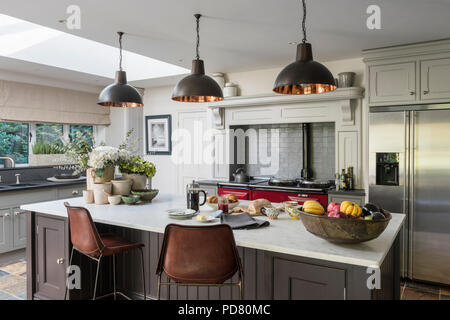 Bespoke kitchen island by Thomas Ford & Sons is painted in Tanner's Brown by Farrow & Ball. Industrial style pendant lights hang above and the bar sto Stock Photo