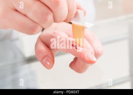 Applying adhesive bandage on bleeding finger Stock Photo