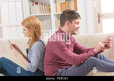 Young couple using their smartphones at home Stock Photo
