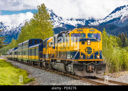 Snow capped mountains in background of Alaska Railroad’s Coastal Classic train from Anchorage to Seward Alaska Stock Photo