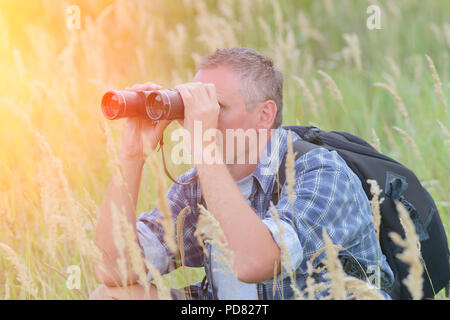 Close up of a man looking through binoculars, outdoors. Stock Photo