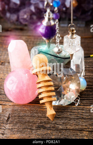 Pendulums.Wooden, crystal pendulum, amethyst, tool for dowsing. Crystals undrneath and in backbround. Stock Photo