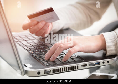 Womans hand holding credit card over notebook, concept of e-commers and mobile payment Stock Photo