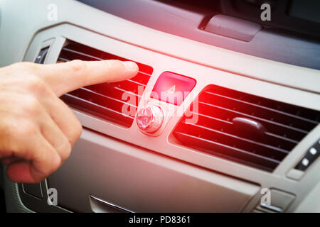 Driver pressing red triangle car hazard warning button Stock Photo